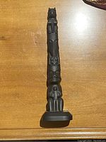 Front view of the 11-inch tall carved indigenous totem pole showing multiple animal and symbolic carvings stacked vertically.