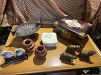 Overview of lot showing metal leaf dish with bird handles, white stone box with flower carving, wooden box with Asian painted motif, wooden vases, and brass elephant figurines.