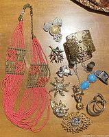 Full lot view showing variety of jewelry pieces including necklace, rings, bracelets, and brooches on wooden surface