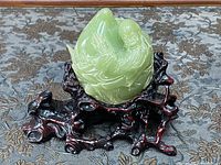 Front view of green jade sculpture showing figure in flowing robes on carved wooden stand.