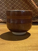 Side view of brown pottery bowl showing rounded shape and smooth glaze.