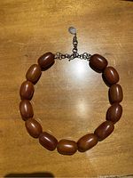 Full view of the amber necklace laid flat showing the beads and clasp.