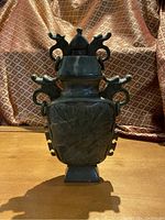 Full front view of the serpentine jade vase showing overall shape, lid, and decorative patterns.