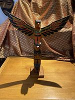 Full front view of carved painted wooden totem pole on stand