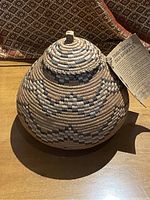 Photo of traditional South African Zulu basket showcasing its conical shape, geometric weaving patterns, and lid with handle.