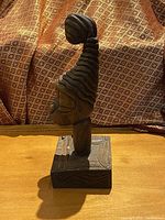 Front view of the wooden African head sculpture on a base, highlighting overall shape and height.