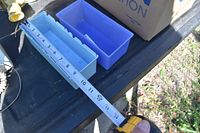Measure of a light blue plastic parts bin showing length around 10-11 inches