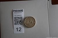 Photo showing 1960 Canadian silver dollar coin next to MaxSold support QR code and lot number.