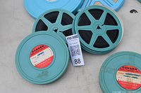 Photo of two blue Carsen Permaflex film reels with black film exposed and plastic cans with red and white label showing the brand and titles.