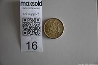 Photo of the coin's reverse featuring detailed Canadian coat of arms including shield and supporters, alongside auction lot number tag.