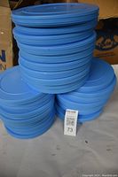 Stack of 30 blue plastic movie reel cases arranged on a surface.