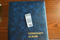 Blue CoinCraft branded coin album binder closed on wooden surface