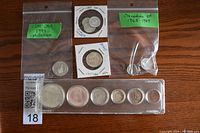 Coins laid out on table showing several Canadian commemorative coins from various years including 1867-1967 and 1999 Millennium quarter.