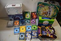 Overview of the lot showing Pokemon collector boxes including Snorlax and Lugia designs, card sleeves, and energy cards
