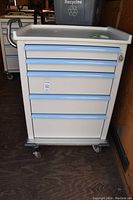 Front of cart showing top tray and five blue-handled drawers.