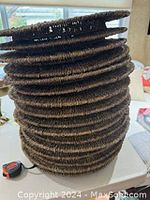 Stack of 16 dark brown wicker chargers showing thickness and texture
