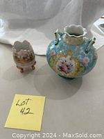 Photo showing the pink and gold egg holder alongside the turquoise round vase with floral patterns and gold accents.