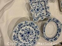 Overview of the blue and white dishes showing the floral painted pattern on square plates and two serving bowls (one oval, one square).