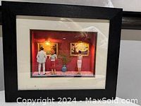 Frontal photo of the framed museum vignette sculpture with three figurines and lit paintings.
