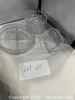 Photo showing three cut crystal glass serving pieces including a round divided dish and two smaller dishes on white fabric.
