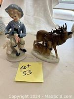 Photo showing both porcelain figurines: 18th century boy with rabbit and Fasold & Stauch elk with calf, placed beside each other