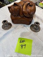 Photo showing wooden cat box and two metal candle holders on a light-colored cloth surface with lot tag visible.