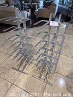 Two modern metal silver-colored book towers placed side by side on tiled floor, showing full height and structure