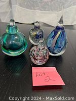 All 4 Murano glass perfume bottles grouped on a dark surface with label indicating lot number