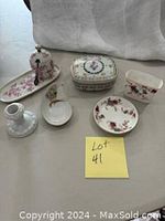 Seven bone china items including candle holder, small plates, pot with spoon, Limoges box, and Minton toothpick holder displayed on a table.