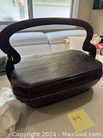 Side angle view of rectangular vintage Chinese wooden box with prominent curved carved handle and dark polished wood showing wear.