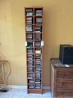 Full wooden CD tower containing numerous CDs in jewel and cardboard cases arranged in vertical columns.