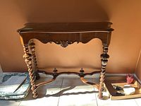 Full front view of dark stained carved wood console table against wall