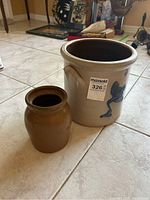 Photo showing both the crock and jug positioned on the floor with background items visible. Focus on relative size and exterior surface details.