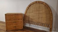 Photo of rattan three drawer dresser and paired rattan curved-top headboard showing overall condition and style.