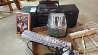 Full lot view showing Sony boombox with two speakers, portable lantern light, clear power bar, and VHS tape.