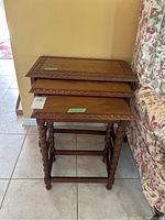 Full stacked view of three nesting tables showing carved wooden tops and twisted legs.