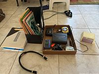 Overall view of sheet music in magazine holder, cassette players, Sony Walkman, pitch-pipe, whistles, and radios, all shown on tiled floor.