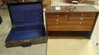Open view of vintage leather valise case alongside wooden multi-drawer tool kit cabinet with drop-down front