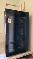 Front view of the black Arctic King wine fridge with glass door and visible digital display.