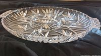 Side angle view of the oval crystal serving tray showing the raised sections and intricate cut starburst designs.