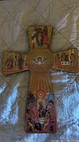 Full view of wooden icon cross showing the five painted scenes and central dove image.