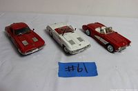 Three 1:24 scale diecast Corvette models: white, red convertible, and red Stingray