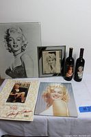 Overview of 6 Marilyn Monroe items including posters, calendar, framed photo clipping, and 2 bottles.