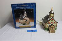 Photo showing the church building out of the box next to the original packaging, showing detailed decoration and electrical cord.