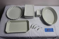 Full view showing all dishes including plates, sauce dishes, cooking dishes, and sauce spoons arranged on white cloth.
