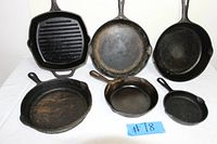 Photo showing six cast iron cookware items including pans and a grill pan.