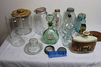 Photo of a variety of vintage jars, bottles, and a ceramic canister with California decorations arranged on a white surface, showing different shapes and sizes.