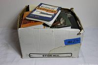 Box containing a mixture of books showing exterior damage and wear to the box itself