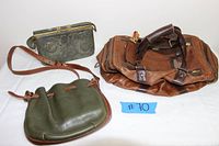Photo shows three leather bags: a large brown rugged duffel bag with handles and buckles, an olive green drawstring crossbody bag with brown adjustable strap, and a dark grey tooled Italian leather frame handbag with metal clasp and embossed floral pattern.