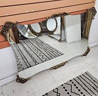 Full view of the large antique mirror with visible brass ornate corners and reflective glass.